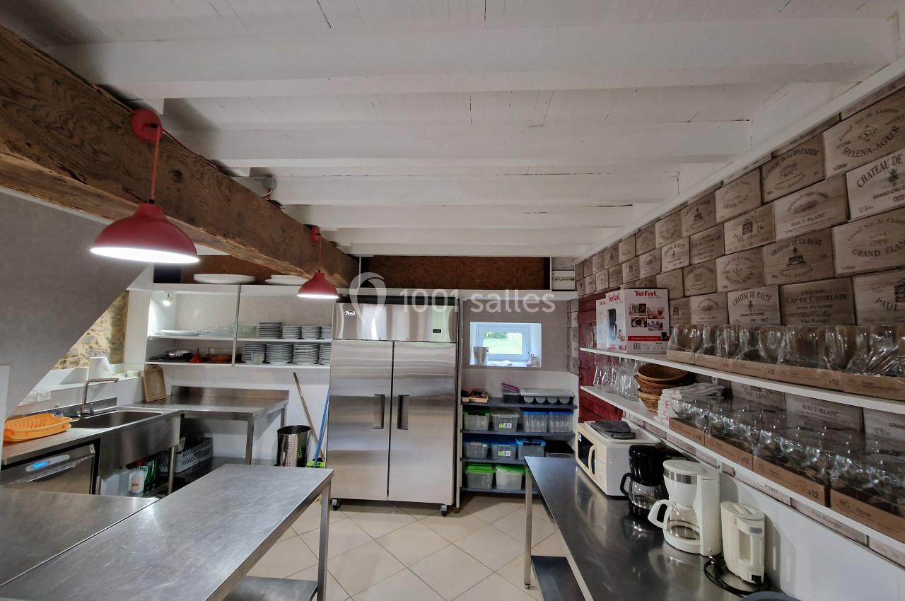 Cuisine professionnelle équipée avec plans de travail en inox, réfrigérateurs, étagères et appareils électroménagers.