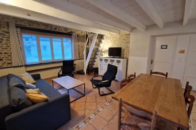 Deux lits avec couvertures bleues et marron dans une chambre lumineuse au sol en parquet et mur clair.