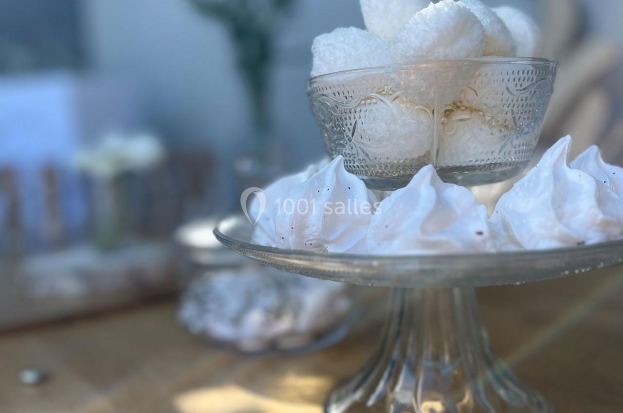 Coupes en verre remplies de meringues blanches sur une table en bois, avec un arrière-plan flou.