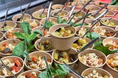 Des portions de nourriture servies dans des pots en carton avec des fleurs blanches en décoration.