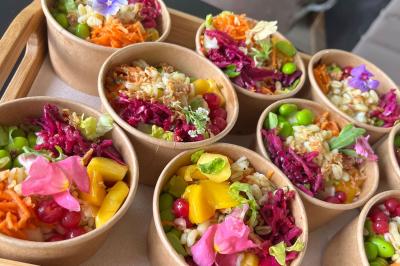 Des portions de nourriture servies dans des pots en carton avec des fleurs blanches en décoration.