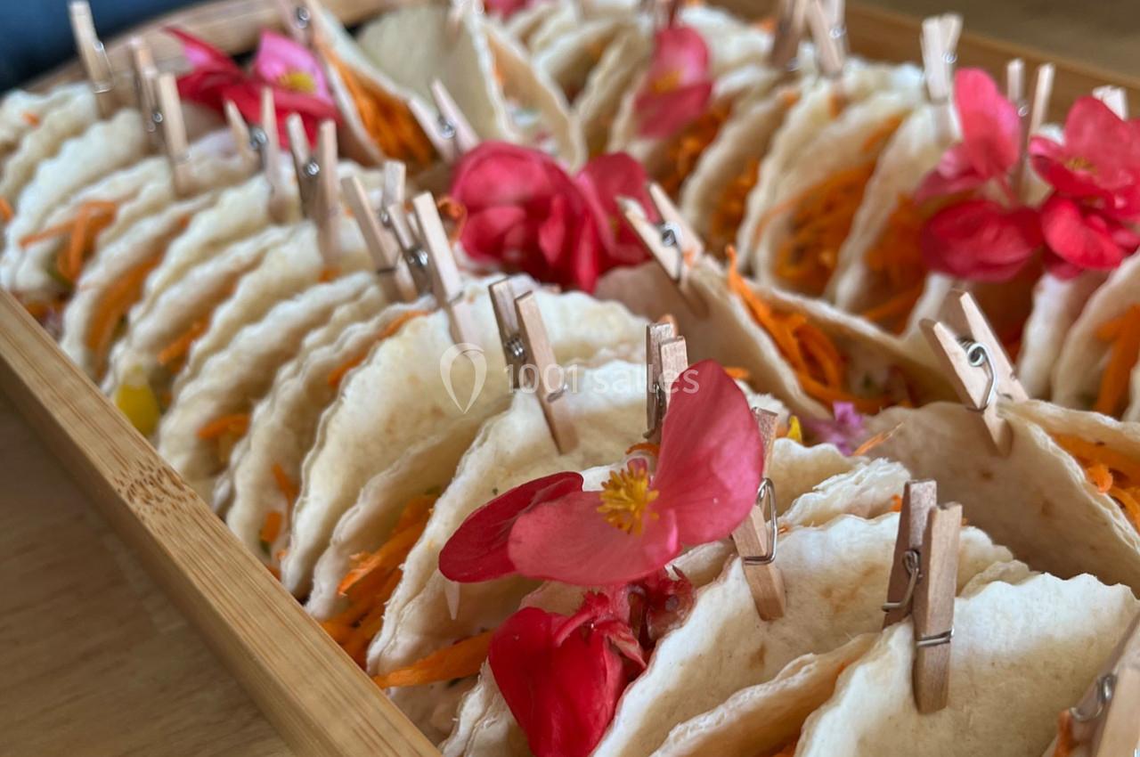 Plateau de mini-tacos garnis de légumes et décorés de fleurs comestibles, maintenus par de petites pinces en bois.