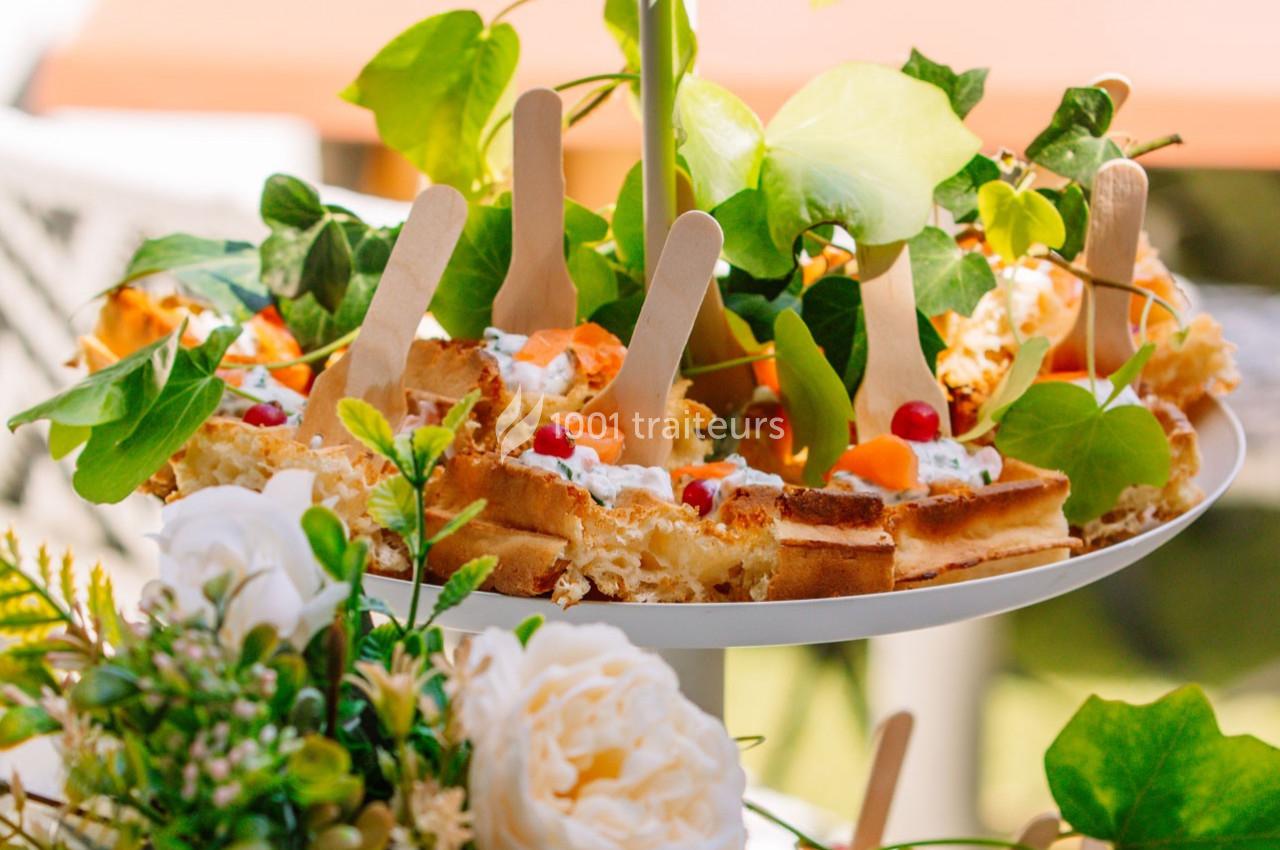 Assiette garnie de gaufres décorées de fruits et de crème, entourée de feuillage et de fleurs.
