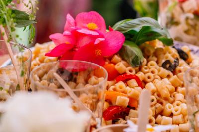 Des portions de nourriture servies dans des pots en carton avec des fleurs blanches en décoration.