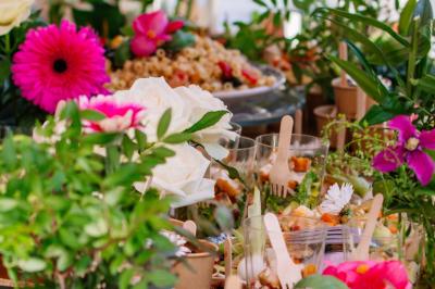 Des portions de nourriture servies dans des pots en carton avec des fleurs blanches en décoration.