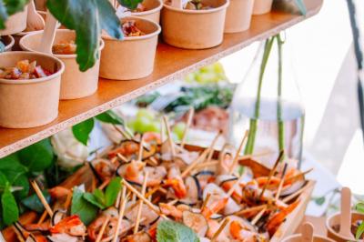 Des portions de nourriture servies dans des pots en carton avec des fleurs blanches en décoration.