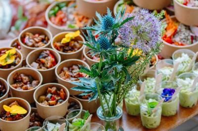 Des portions de nourriture servies dans des pots en carton avec des fleurs blanches en décoration.