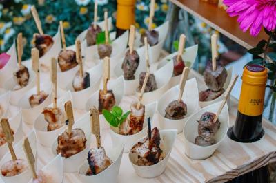 Des portions de nourriture servies dans des pots en carton avec des fleurs blanches en décoration.