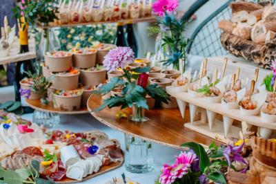 Des portions de nourriture servies dans des pots en carton avec des fleurs blanches en décoration.
