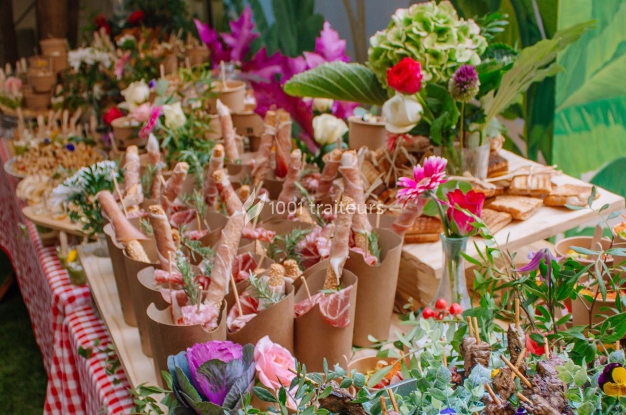 Table garnie de fleurs colorées et de mets variés présentés dans des contenants en carton, ambiance festive et naturelle.