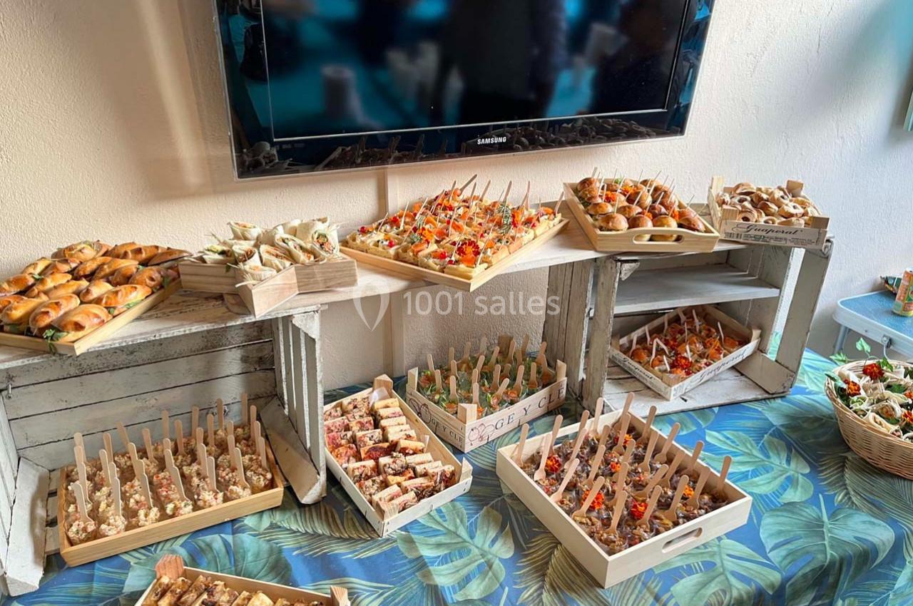 Buffet de bouchées apéritives variées présentées sur des plateaux en bois, disposés sur une table décorée de motifs…