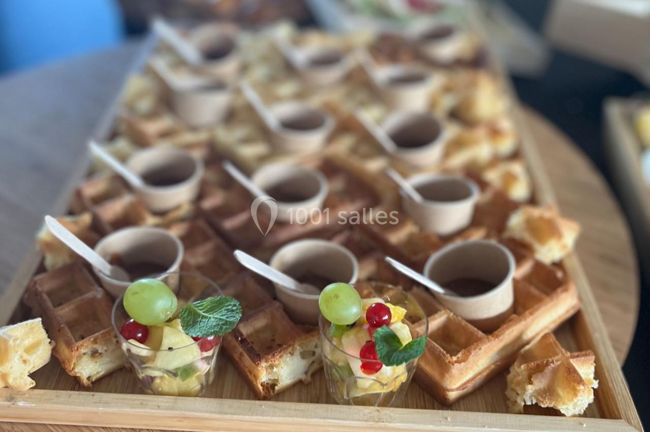 Plateau de gaufres dorées avec des verrines de fruits et des pots individuels de sauce, disposés pour un buffet.