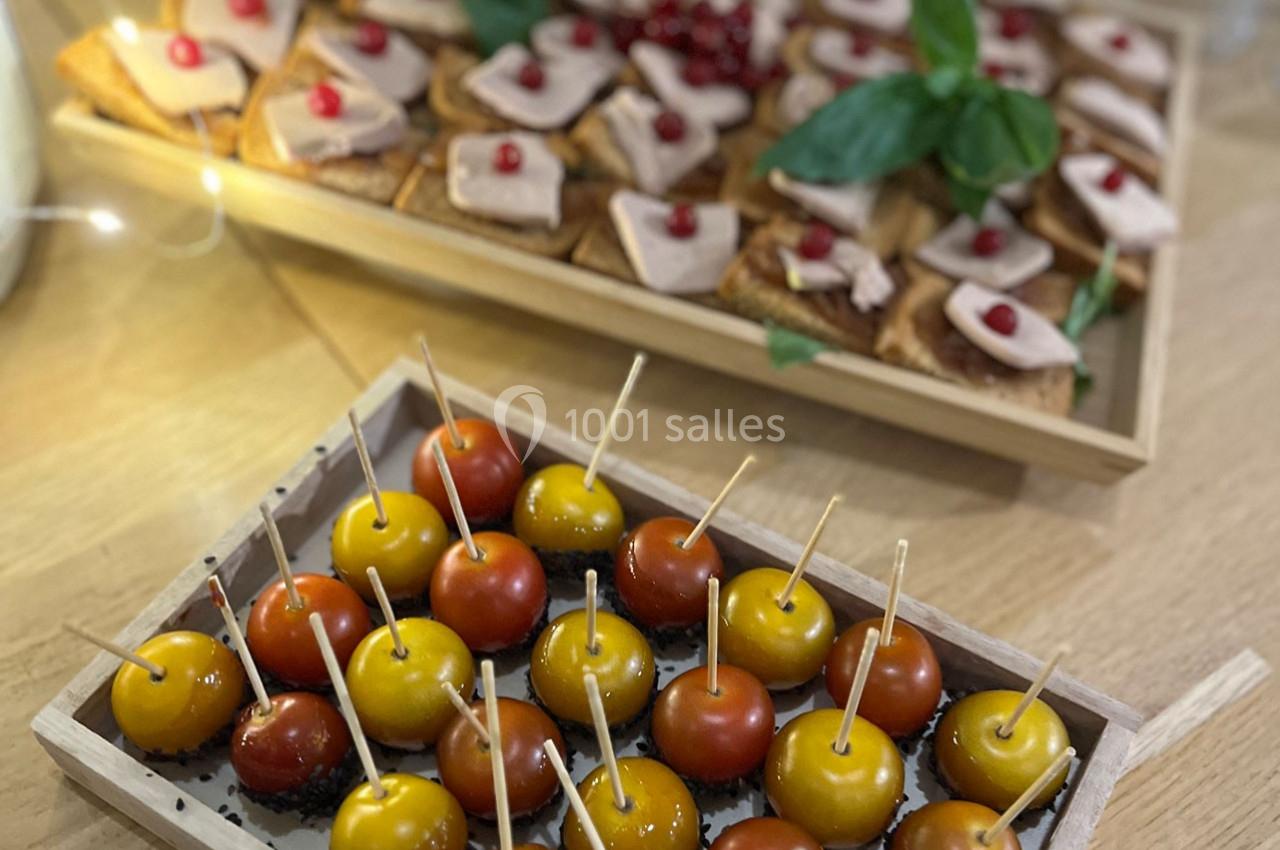Plateau de mini pommes d'amour et toasts garnis de foie gras et de grains de grenade sur une table en bois.