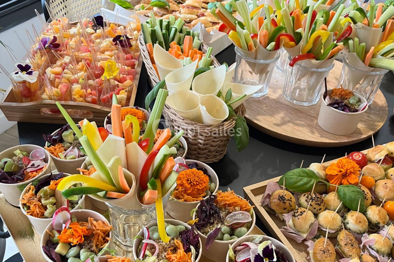 Buffet coloré composé de légumes frais, verrines, brochettes de fruits et petits pains garnis.
