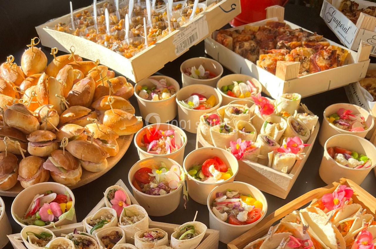 Buffet varié avec mini-sandwichs, verrines, wraps et desserts présentés dans des contenants individuels.