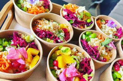 Des portions de nourriture servies dans des pots en carton avec des fleurs blanches en décoration.