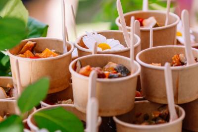 Des portions de nourriture servies dans des pots en carton avec des fleurs blanches en décoration.