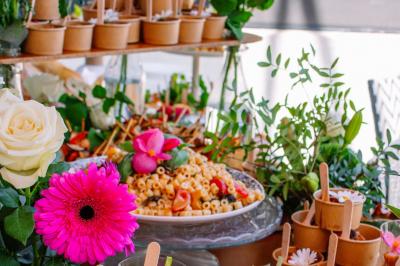 Des portions de nourriture servies dans des pots en carton avec des fleurs blanches en décoration.
