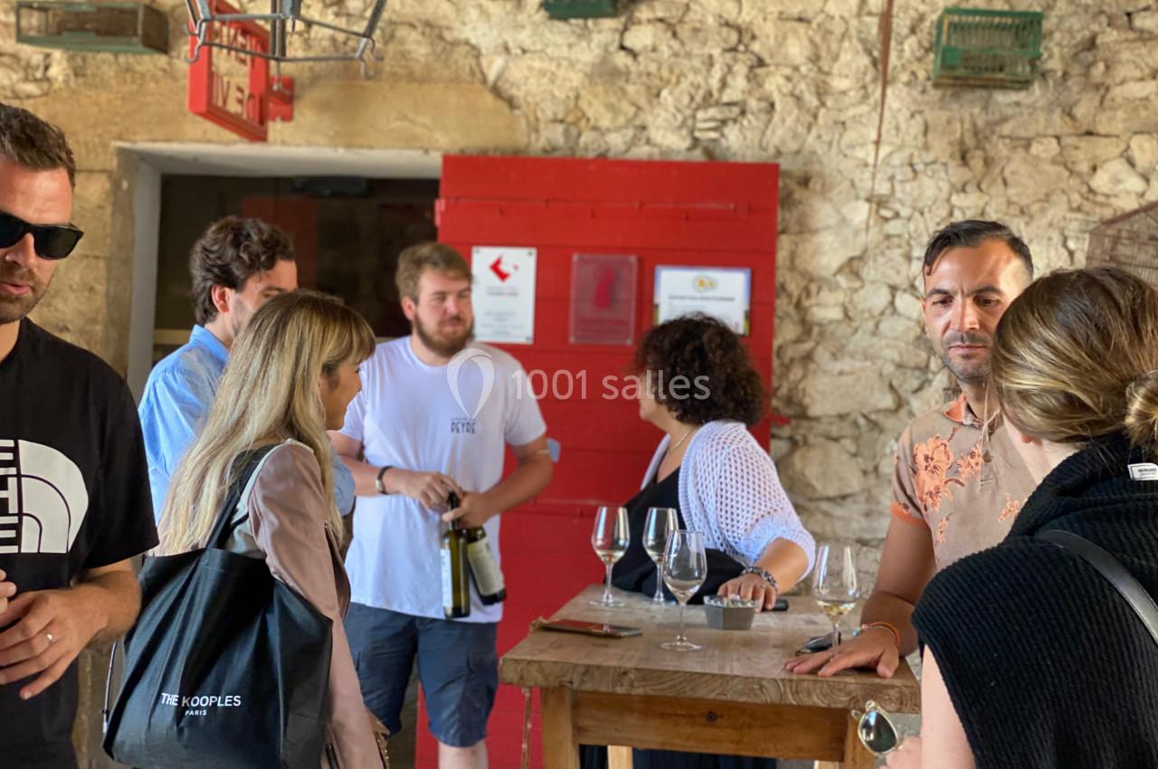 Groupe de personnes discutant autour d'une table en bois dans un espace intérieur à murs en pierre.