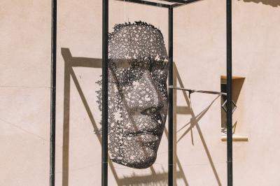 Vue aérienne d'un domaine rural avec bâtiments en pierre, cour pavée, arbres et champs environnants.