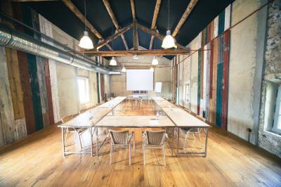 Vue aérienne d'un domaine rural avec bâtiments en pierre, cour pavée, arbres et champs environnants.