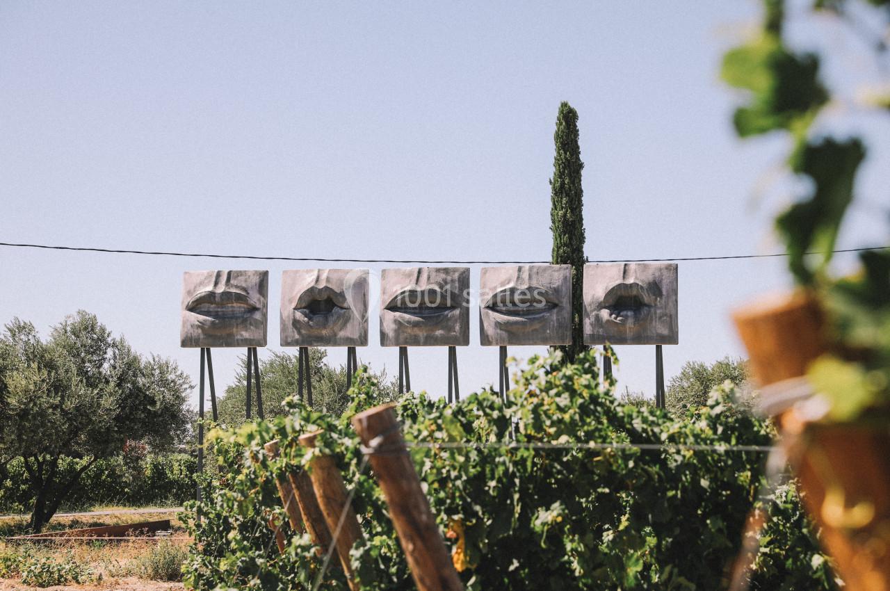 Quatre panneaux représentant des lèvres dans un paysage rural avec des vignes et des arbres en arrière-plan.