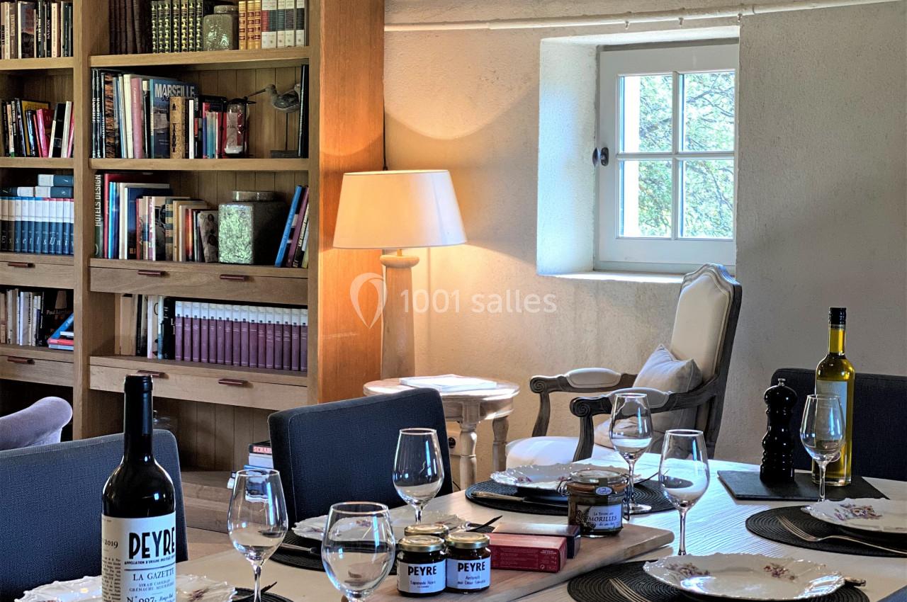 Table dressée dans une salle lumineuse avec bibliothèque en bois, lampadaire et fenêtre donnant sur l'extérieur.