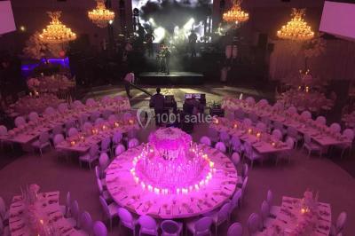 Piscine éclairée de nuit entourée de chaises longues, avec une terrasse en premier plan et des bougies allumées.