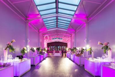 Piscine éclairée de nuit entourée de chaises longues, avec une terrasse en premier plan et des bougies allumées.