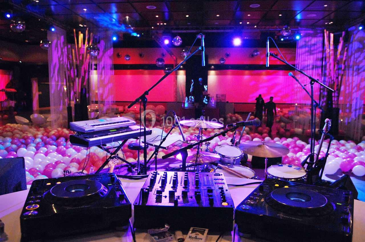 Matériel de DJ et instruments installés sur une scène, avec des ballons colorés et des lumières en arrière-plan.