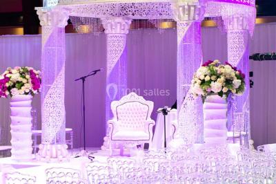 Piscine éclairée de nuit entourée de chaises longues, avec une terrasse en premier plan et des bougies allumées.