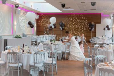 Piscine éclairée de nuit entourée de chaises longues, avec une terrasse en premier plan et des bougies allumées.