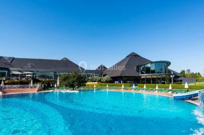 Piscine éclairée de nuit entourée de chaises longues, avec une terrasse en premier plan et des bougies allumées.