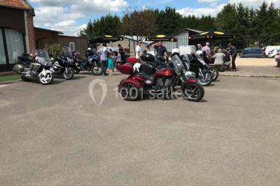 Un grand saule ombrageant un espace détente avec des palettes aménagées et des coussins sur une pelouse.