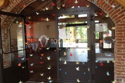 Un grand saule ombrageant un espace détente avec des palettes aménagées et des coussins sur une pelouse.