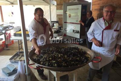 Un grand saule ombrageant un espace détente avec des palettes aménagées et des coussins sur une pelouse.