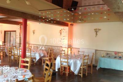 Un grand saule ombrageant un espace détente avec des palettes aménagées et des coussins sur une pelouse.