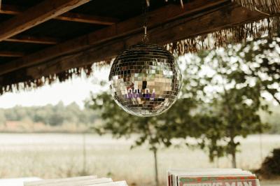 Un DJ mixe à l'extérieur depuis un stand aménagé dans un véhicule, avec des tables et des personnes en arrière-plan.