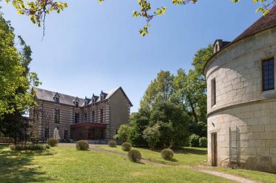 Un vélo décoré de fleurs blanches et vertes est appuyé contre une grille en fer forgé dans un cadre arboré.