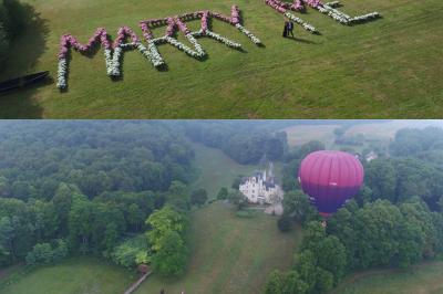 Un vélo décoré de fleurs blanches et vertes est appuyé contre une grille en fer forgé dans un cadre arboré.