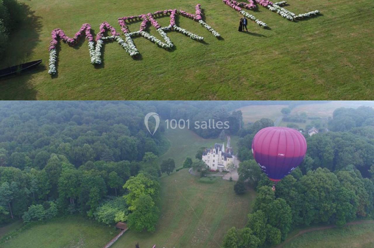 Vue aérienne d'une demande en mariage avec des fleurs formant ’Marry Me’ sur une pelouse, près d'un château et d'une…