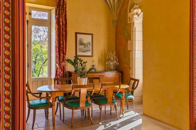 Un vélo décoré de fleurs blanches et vertes est appuyé contre une grille en fer forgé dans un cadre arboré.