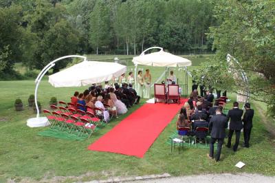 Un vélo décoré de fleurs blanches et vertes est appuyé contre une grille en fer forgé dans un cadre arboré.