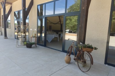 Un vélo décoré de fleurs blanches et vertes est appuyé contre une grille en fer forgé dans un cadre arboré.