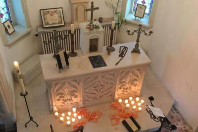 Un vélo décoré de fleurs blanches et vertes est appuyé contre une grille en fer forgé dans un cadre arboré.