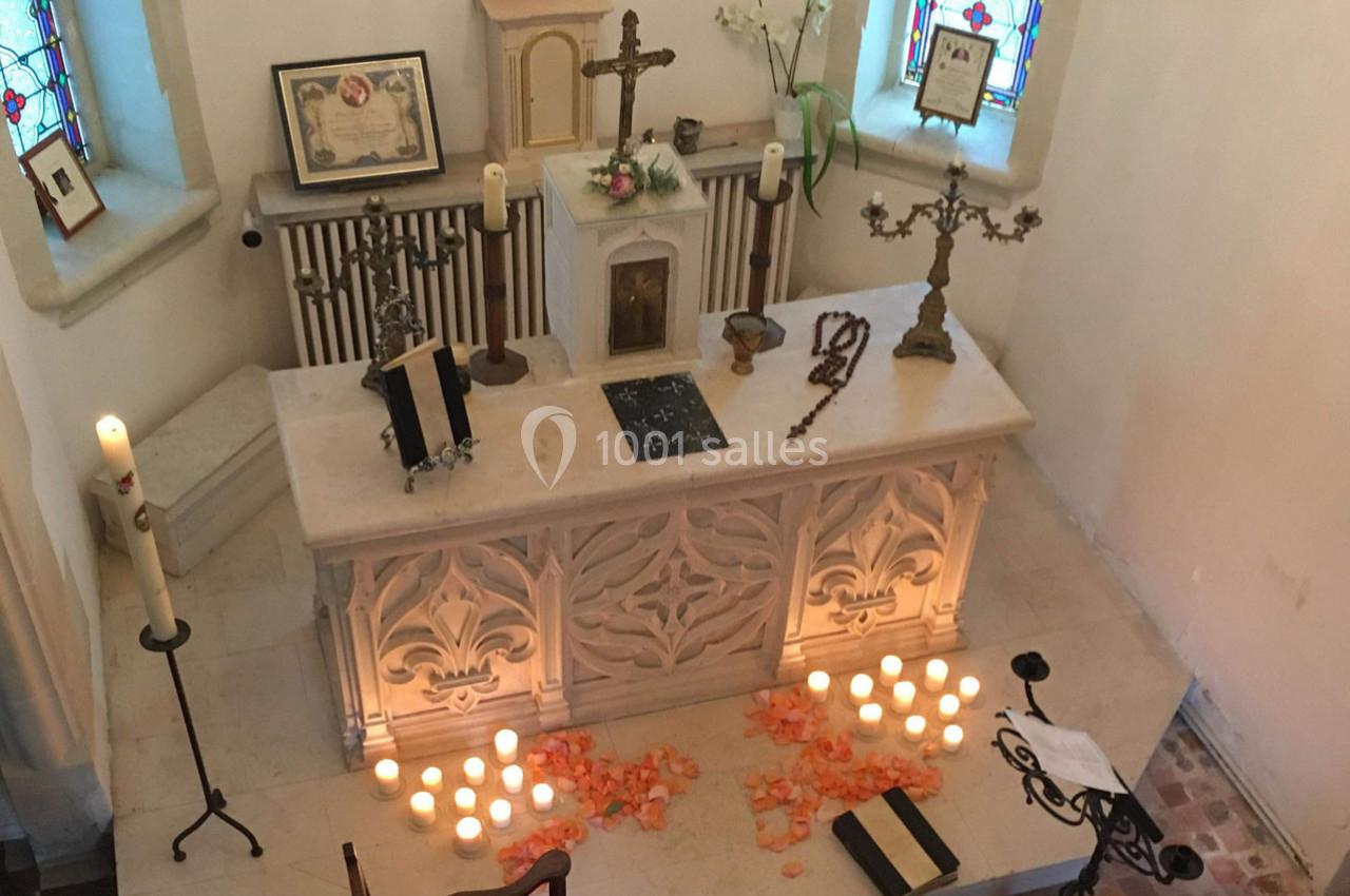 Autel d'église décoré de bougies, pétales de fleurs, croix et objets religieux, entouré de vitraux colorés.