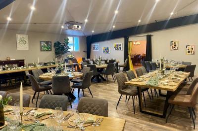 Coucher de soleil rougeoyant derrière une rangée d'arbres, vu depuis une terrasse avec mobilier et voitures garées.