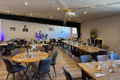 Coucher de soleil rougeoyant derrière une rangée d'arbres, vu depuis une terrasse avec mobilier et voitures garées.