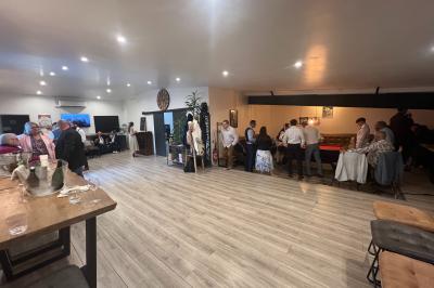 Coucher de soleil rougeoyant derrière une rangée d'arbres, vu depuis une terrasse avec mobilier et voitures garées.