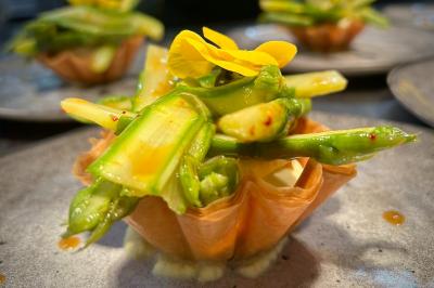 Coucher de soleil rougeoyant derrière une rangée d'arbres, vu depuis une terrasse avec mobilier et voitures garées.